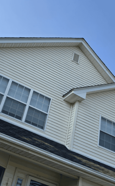 Siding wall meeting a lower roof slope, the joint where step and kickout flashing stop leaks on Hicksville split-levels and dormers